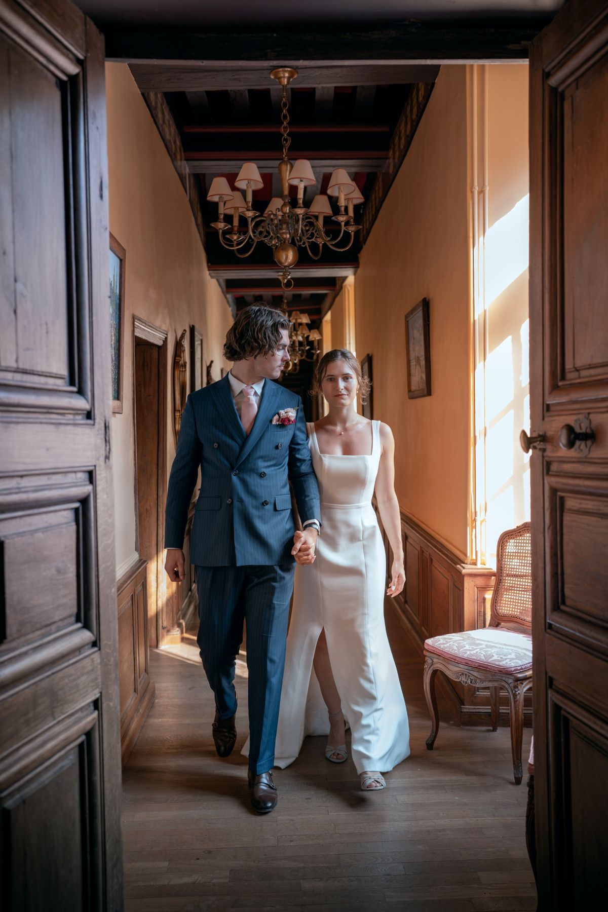 Les mariés main dans la main dans un couloir du château